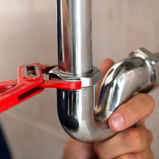 Man fixing a pipe with a red spanner