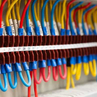 Variety of blue, red and yellow wires, connected to an electrical switch board