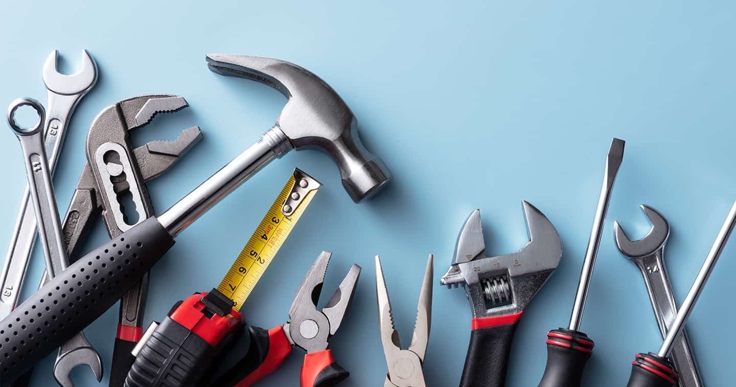 A variety of tools including a hammer, tape measure and pliers on a blue background