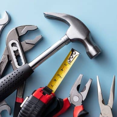 A variety of tools including a hammer, tape measure and pliers on a blue background