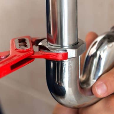 Red spanner tightening a pipe fixture