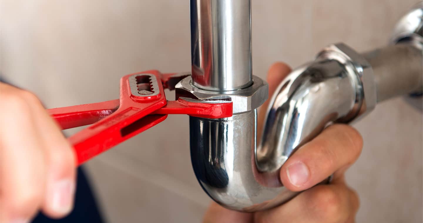 Red spanner tightening a pipe fixture